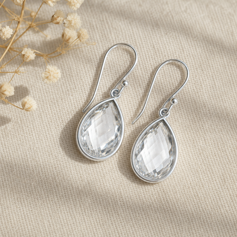 Zilveren oorhangers met gefacetteerde druppelvormig in kap gezette edelstenen · Bergkristal · flatlay · steen:bergkristal