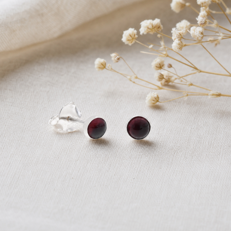 Zilveren oorknopjes met rond in kap gezette edelstenen 2 · Granaat · flatlay · steen:granaat