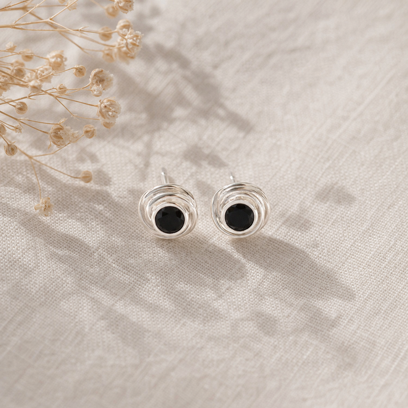 Zilveren oorknopjes met spiraalvormig gezette rond gefacetteerde edelstenen · Onyx · flatlay · steen:onyx