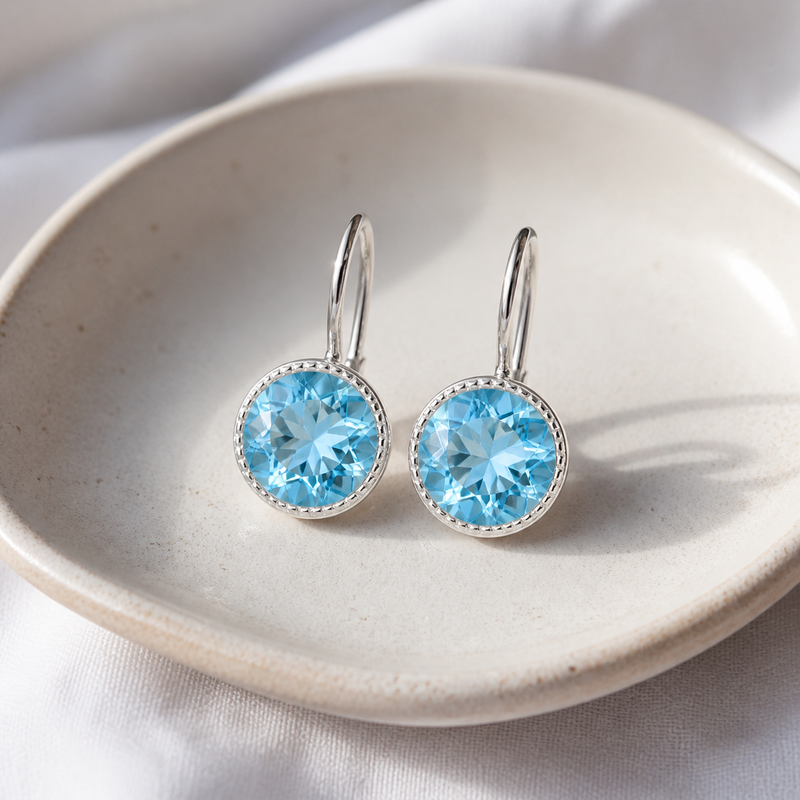 Zilveren oorhangers met rond gefacetteerd in kap gezette edelsteen - 925 zilver - 10 mm · Blauwe Topaas · sfeerbeeld · steen:blauwe-topaas
