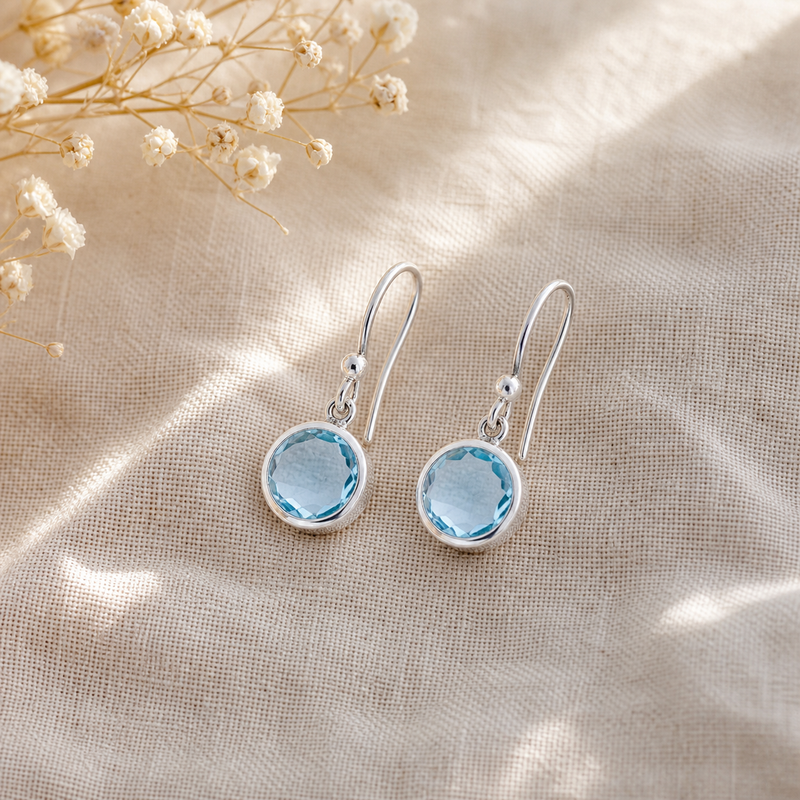 Zilveren oorhangers met rond gladgeslepen in kap gezette edelstenen · Blauwe Topaas · flatlay · steen:blauwe-topaas