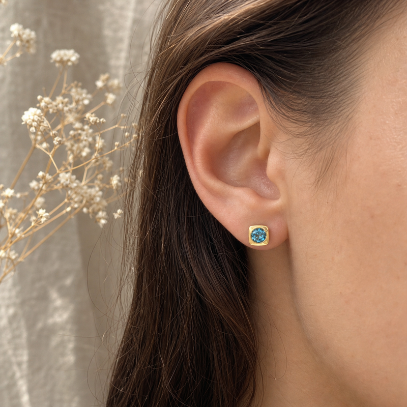 Gouden oorstekers met Blauwe Topaas edelstenen · Blauwe Topaas · flatlay · steen:blauwe-topaas