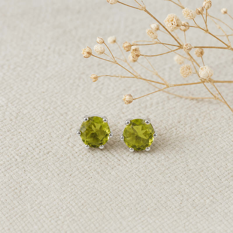 Zilveren oorknopjes met rond gefacetteerd in klauw gezette edelstenen · Peridoot · flatlay · steen:peridoot
