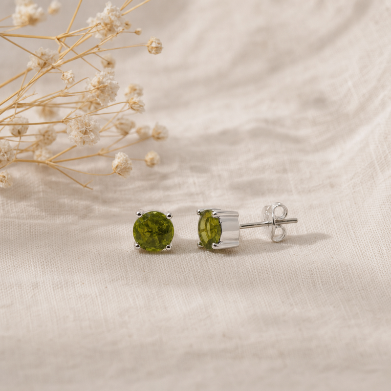 Zilveren oorknopjes met rond gefacetteerde in klauwzetting gezette edelstenen · Peridoot · flatlay · steen:peridoot