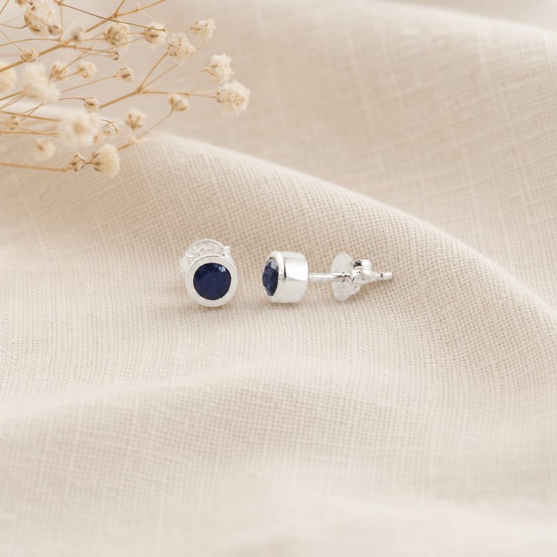 Zilveren oorknopjes met rond glad in kap gezette edelstenen · Saffier · flatlay · steen:saffier